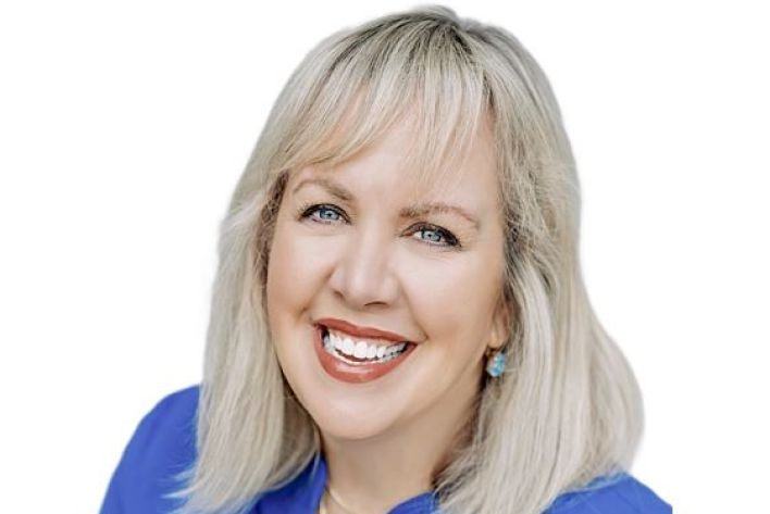 Side view of a businesswoman holding a microphone while addressing an audience at a conference.